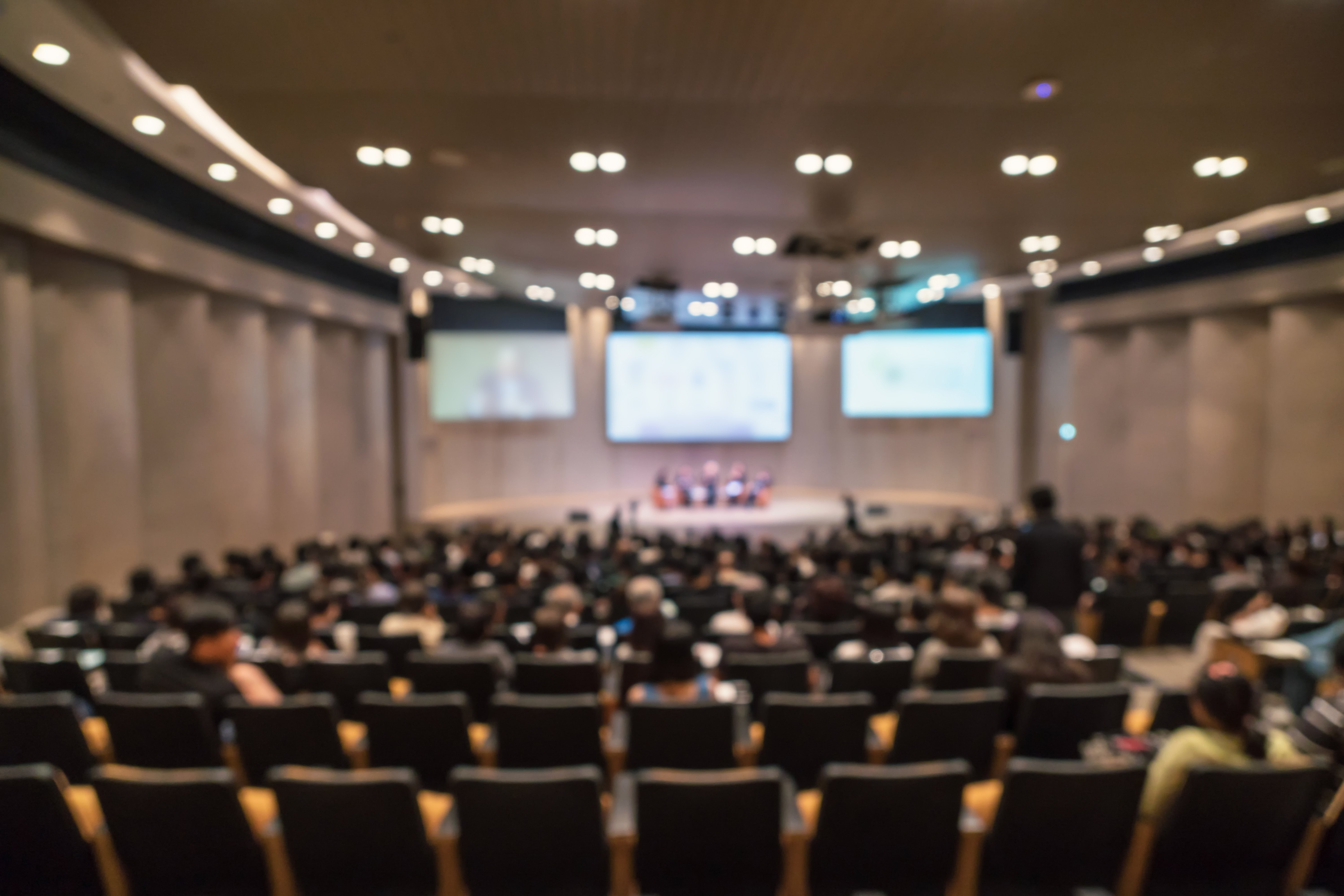 abstract-blurred-photo-conference-hall-seminar-room-with-speakers-stage